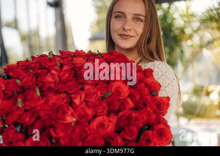 Glückliche junge Frau hat einen großen Rosenstrauß. Stockfoto