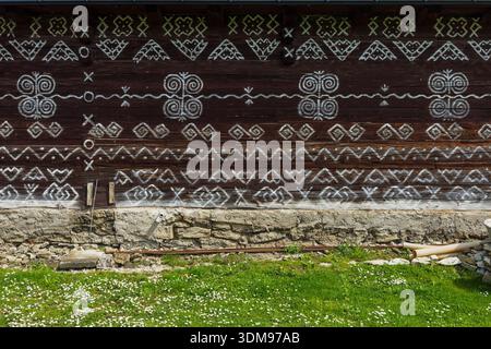 Holzwand mit einzigartigen geometrischen Mustern auf dunklem Hintergrund in Cicmany, Slowakei Stockfoto