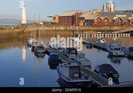 Newhaven Harbour im Winter mit Fischerbooten und verankerten Schiffen bei Flut, mit dem weißen Leuchtturm am Pier Place, Edinburgh, Schottland, Großbritannien Stockfoto