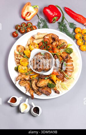 Gegrilltes Hühnerteilchen mit Gemüse, Sesampilzen und Saucen von oben Stockfoto