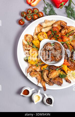 Gegrilltes Hühnerteilchen mit Gemüse, Sesampilzen und Saucen von oben Stockfoto