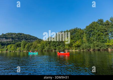 Beynac-et-Cazenac, Frankreich: 20. August 2024: Farbenfrohe Kajaks auf dem ruhigen Fluss Dordogne, umgeben von üppigen grünen Bäumen Stockfoto