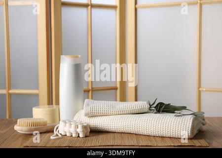 Reinigen Sie Waffelhandtücher, Eukalyptuszweige und Kosmetikprodukte auf Holztisch drinnen Stockfoto