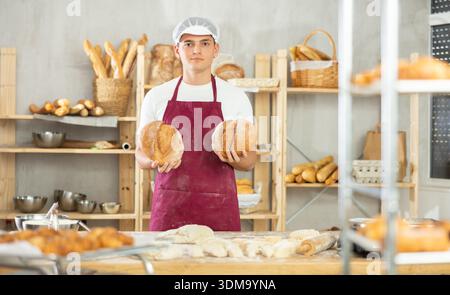 Bäckerei männlicher Mitarbeiter hält fertiges Brot in der Hand Stockfoto