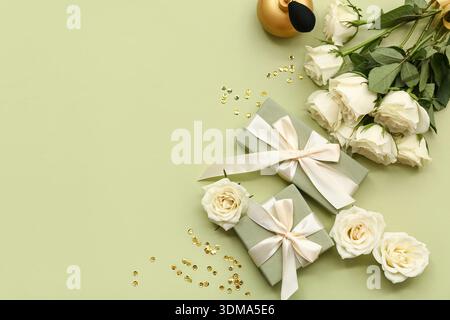 Komposition mit Geschenkboxen, weißen Rosenblüten und einer Flasche Parfüm auf grünem Hintergrund Stockfoto