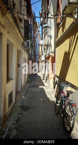 Ein Fahrrad parkt in einer engen, sonnigen Gasse zwischen alten Gebäuden, Slowenien Stockfoto