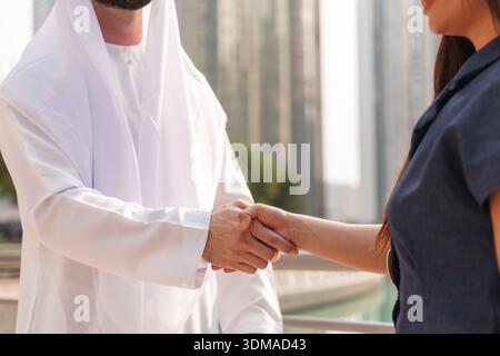 In internationalen Geschäftsumgebungen schließen ein Geschäftsmann aus dem Nahen Osten und eine asiatische Geschäftsfrau ein Handelsabkommen ab. Stockfoto