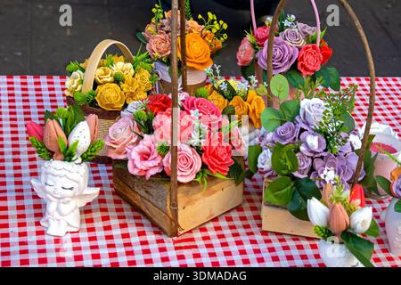 Farbenfrohe, schöne künstliche Blumen in Holzkörben auf dem Tisch im Inneren des Zimmers Stockfoto