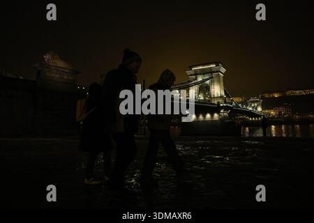 Budapest, Ungarn, Ungarn. Februar 2026. Nachts spazieren die Menschen entlang der Donau mit der Szechenyi Kettenbrücke im Hintergrund in Budapest. (Kreditbild: © Bianca Otero/ZUMA Press Wire) NUR REDAKTIONELLE VERWENDUNG! Nicht für kommerzielle ZWECKE! Stockfoto