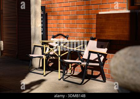 Stühle und Tisch im Freien vor der sonnendurchfluteten Wand Stockfoto