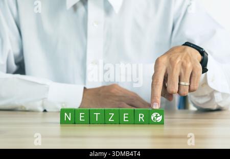 Geschäftsmann Hand hält mit grünem Netzzentrum-Symbol und grünem Symbol auf grauem Hintergrund. Null- und CO2-neutrale Konzepte Null-Nettoemissionsziele Stockfoto