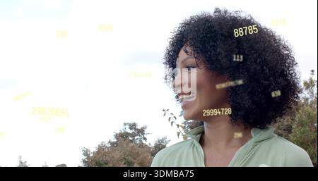 Lächelnde Frau mit grünem Reißverschluss über hellem Himmel und Bäumen, gelbe Datenüberlagerungen, Kopierraum Stockfoto