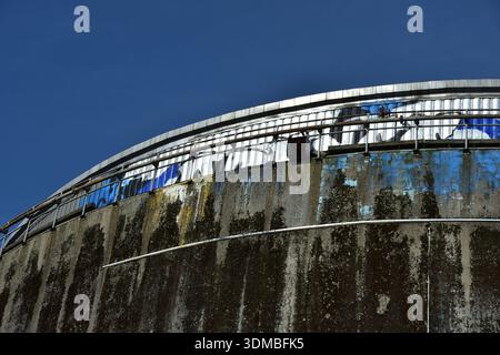 Altes Betonsilo mit blauen Graffiti vor tiefblauem Himmel – industrieller Niedergang Stockfoto
