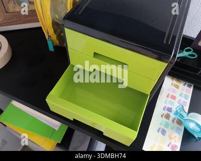 Grüne Kunststoffbox mit herausziehbaren Schubladen für Bürobedarf. Nahaufnahme des Layouts. Raum in einem Raum organisieren. Lagerung von Gegenständen, Büro Stockfoto