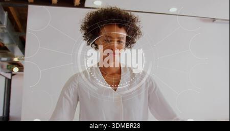 Stehende Frau mit weißer Bluse und Anhänger, die im Studio posiert, mit HUD-Überzug im weißen Hintergrund Stockfoto