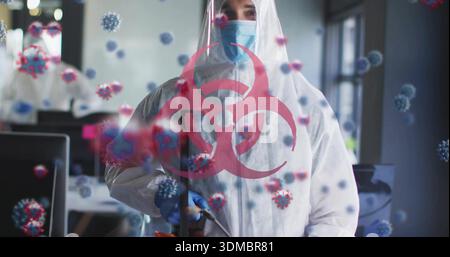 Nebeltechnologie trägt weißen Anzug blaue Maske und Handschuhe, die Nebelspray im Büro mit Biohazard-Symbol halten Stockfoto