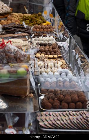 Auswahl an handgefertigten Schokoladentrüffeln, Süßigkeiten und verschiedenen Süßwaren, die an einem Marktstand im Freien zum Verkauf angeboten werden Stockfoto