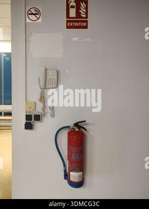 Vertikales Foto einer Umkleidekabine eines Firmenangestellten. An der Wand hängt ein Feuerlöscher, ein internes Telefon, Steckdosen, ein Schalter Stockfoto