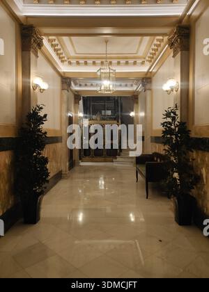 Detail der alten und schönen Lobby eines Wohngebäudes in Barcelona bei Nacht. Marmorboden, warmes Licht, Käfigaufzug. Barcelona in Spai Stockfoto