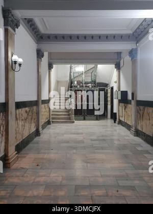 Detail des Innenraums der Lobby eines alten Wohngebäudes in Barcelona, Dekoration ​​simple mit Marmorboden und schmiedeeisernem Käfig eleva Stockfoto