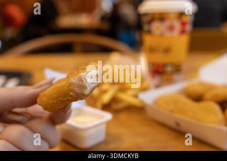 Posen, Polen - 19. November 2025: Nahaufnahme eines goldgebratenen Hühnchennugget mit weißer Dippsoße Stockfoto
