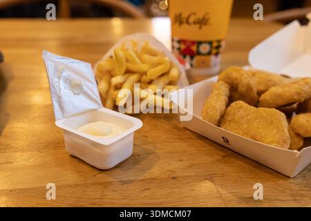 Posen, Polen - 19. November 2025: Ein McDonald's McCafe-Getränk, knusprige goldene Chicken Nuggets, frische Pommes frites und eine offene Dip-Sauce Stockfoto