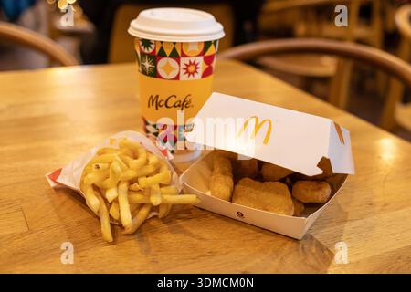 Posen, Polen - 19. November 2025: McDonald's Fast Food-Artikel, McCafe-Kaffee, goldene Chicken Nuggets und knusprige Pommes frites, auf einem Holzkaffee angeordnet Stockfoto