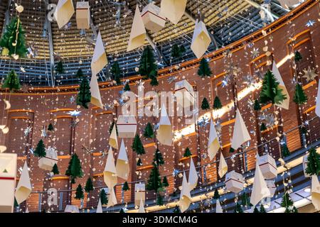 Posen, Polen – 19. November 2025: Dekorative Weihnachtsbäume aus Papier, glänzende Sterne und Gondelformen, die an einer Decke hängen und an eine Freude erinnern Stockfoto