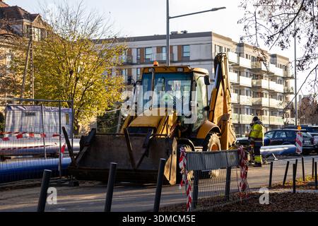 Poznan, Polen – 19. November 2025: Aktiver Stadtbau mit gelbem Baggerlader und Arbeiter veranschaulicht die Entwicklung der Infrastruktur Stockfoto