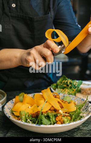 Koch schneidet Karotten für gesunde vegetarische Salatzubereitung Stockfoto