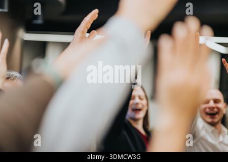 Eine Gruppe von Freunden und Kollegen feiert, lächelnd und händelnd in einem fröhlichen Moment zusammen Stockfoto