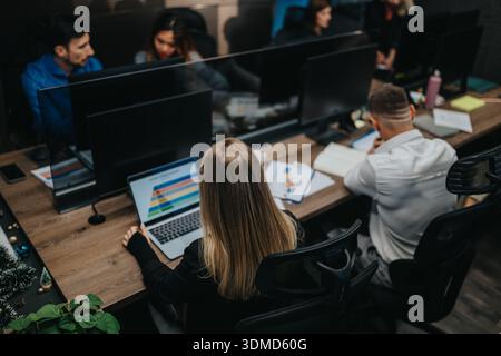 Team von Geschäftsleuten, die an einem gemeinsamen Schreibtisch mit Laptops in einem modernen Büro arbeiten Stockfoto
