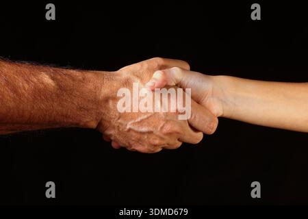 Handschlag zwischen zwei Händen vor dunklem Hintergrund – Nahaufnahme von Form, Textur, Verbindung und gegenseitiger Interaktion durch ein Unternehmen Stockfoto