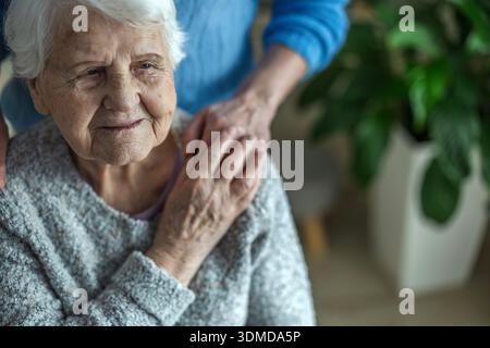 Ältere Frau, die Hände mit ihrer Betreuerin in einem Pflegeheim hält, Nahaufnahme Stockfoto