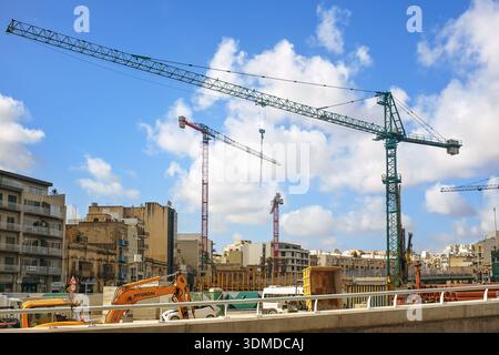 Msida, Malta - 2. Februar 2026: Schwere Maschinen und Turmkräne arbeiten an einem großangelegten Stadtentwicklungsprojekt unter blauem Himmel in der Stadt. Stockfoto