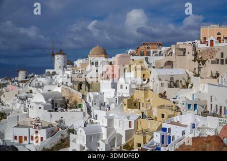 Oia, Apano Meria oder Pano Meria. Traditionelle weiß getünchte kykladische Häuser, Kuppeln und historische Windmühlen mit Blick auf die Ägäis, Santorin reisen. Stockfoto