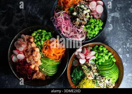 Drei Schüsseln mit Speisen in verschiedenen Farben und Texturen, einschließlich Karotten, Avocados und Radieschen Stockfoto