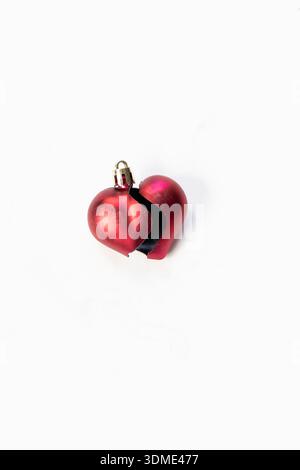 Ein symbolisches Foto mit einem kleinen Herzen als Weihnachtsanhänger vor weißem Hintergrund zum Thema allein an Feiertagen, Liebe, Einsamkeit, Single Stockfoto