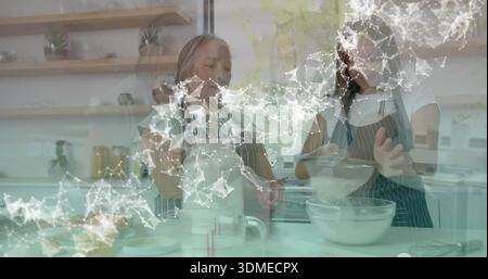 Gemischt Senioren und Teenager mit gestreiften Schürzen an der Haustheke mit Metallsieb und Glasschale Stockfoto