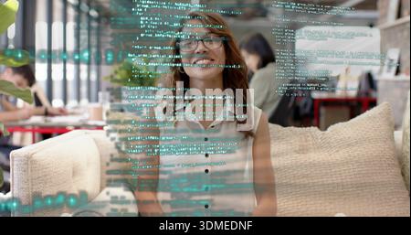 Lächelnde Frau mit Brille, ärmellose weiße Bluse auf Sofa im Café, mit Code-Overlay Stockfoto