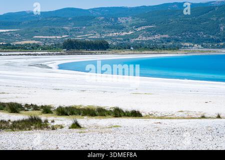 Weiße Sandküste, die sich neben dem türkisfarbenen Wasser des Salda Sees unter klarem blauem Himmel kurvt, einzigartige Mondlandschaft in Burdur, Türkei Stockfoto