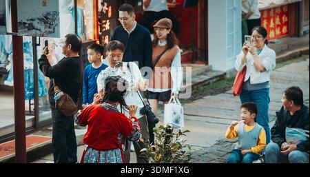 Traditionell gekleidete einheimische Frau interagiert mit sstkChinaisten auf dem Markt. Stockfoto