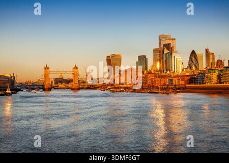 Goldener Sonnenaufgang Blick auf die Skyline von London, England, mit Sonnenlicht reflektiert in den Fassaden der modernen Wolkenkratzer an der City und Tower Bridge Stockfoto