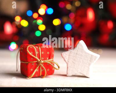 Rote Geschenkbox mit weißer Sternform und Weihnachtslichtern im Hintergrund Stockfoto