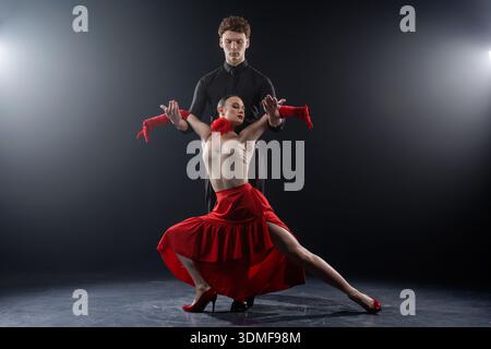 Tanzpaar im Ballsaal, das eine kontrollierte ausdrucksstarke Pose in einer Studioumgebung spielt. Geeignet für Werbebanner, Websites und visuelle Inhalte Stockfoto