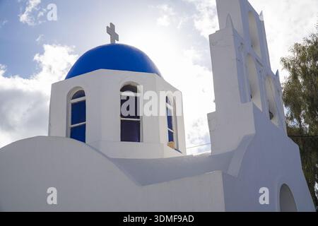 Kleine griechisch-orthodoxe Kirche mit blauer Kuppel und weiß getünchten Wänden in Fira, Santorin, Griechenland. Ikonische Architektur der Kykladen in der Nähe des Citizen Service CEN Stockfoto