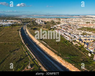 Panoramablick auf Villamartin an der Costa Blanca, Spanien, mit Wohnvierteln mit Häuserreihen, Gewerbezonen und Autobahn Stockfoto