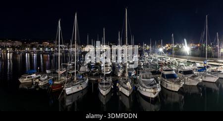 Puerto de La Spezia iluminado por la noche, Italien. Vista nocturna del puerto con barcos, grúas industriales y luces reflejadas en el Agua. Italia Stockfoto