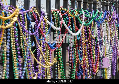 Nahaufnahme vieler bunter mardi Gras Perlen, die an einem Zaun hängen Stockfoto