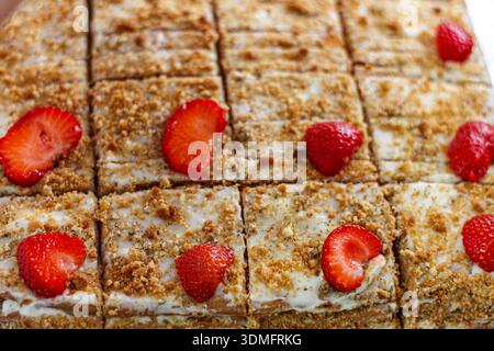 Nahaufnahme von frisch gebackenen Kuchenscheiben mit Reifen Erdbeeren und Sahne in einer lokalen Bäckerei. Stockfoto